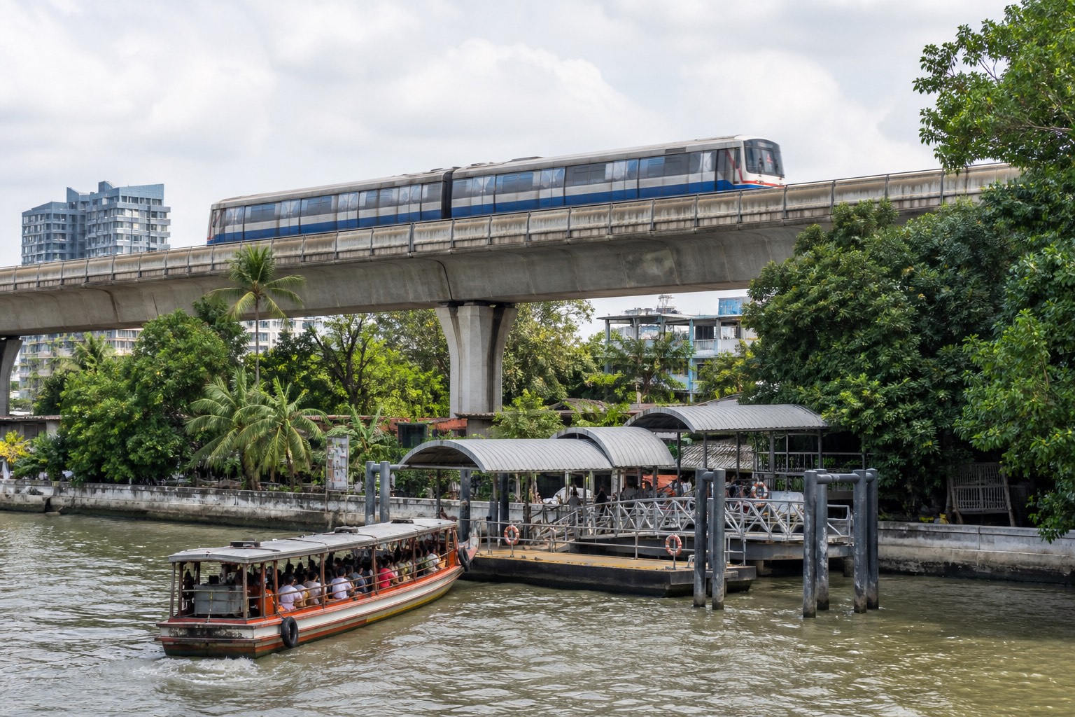 Tren elevado y barco de pasajeros junto a un muelle urbano de Bangkok
